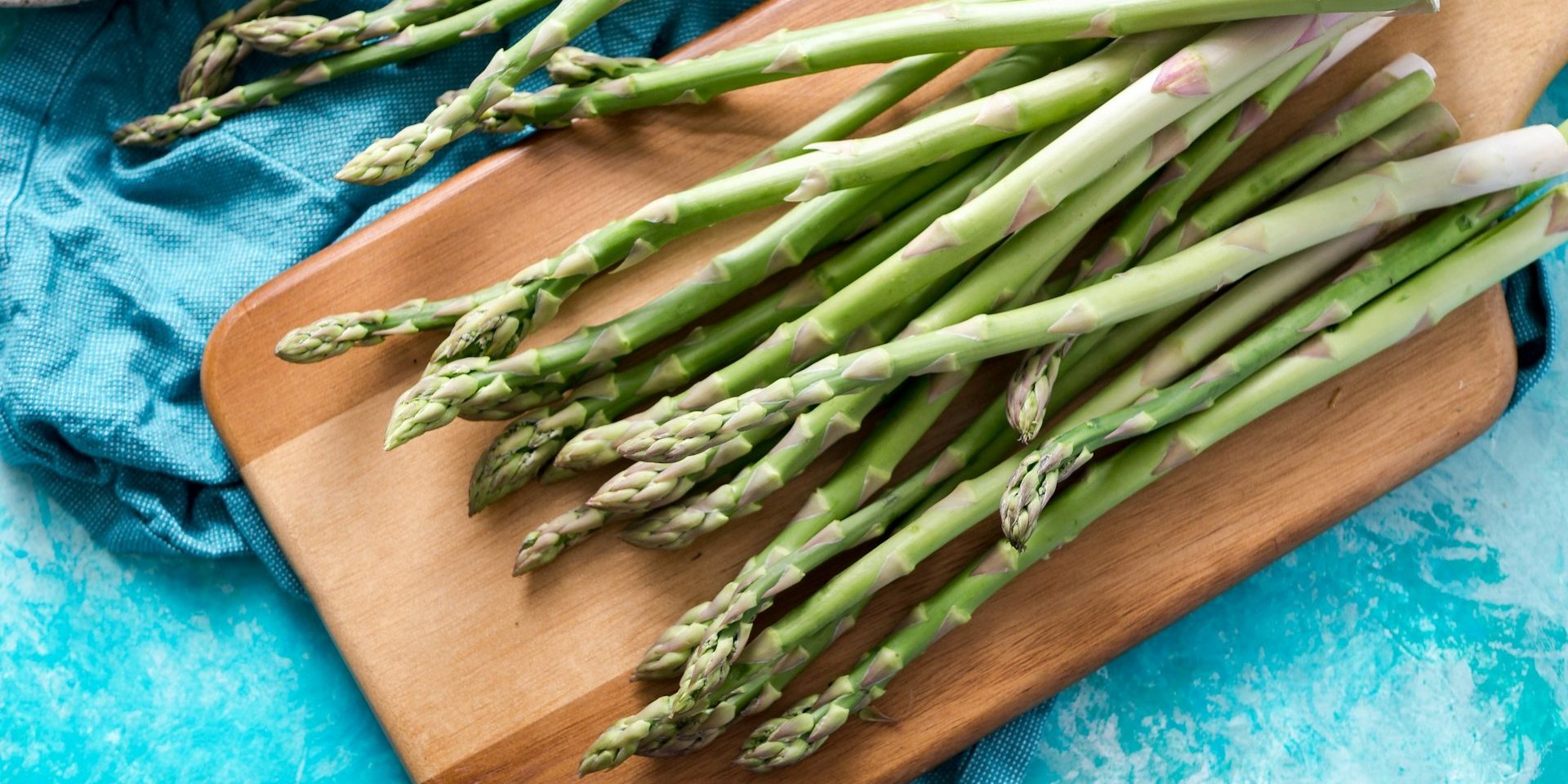 Verse groene asperges op een houten plank, perfect voor combinaties met kruiden